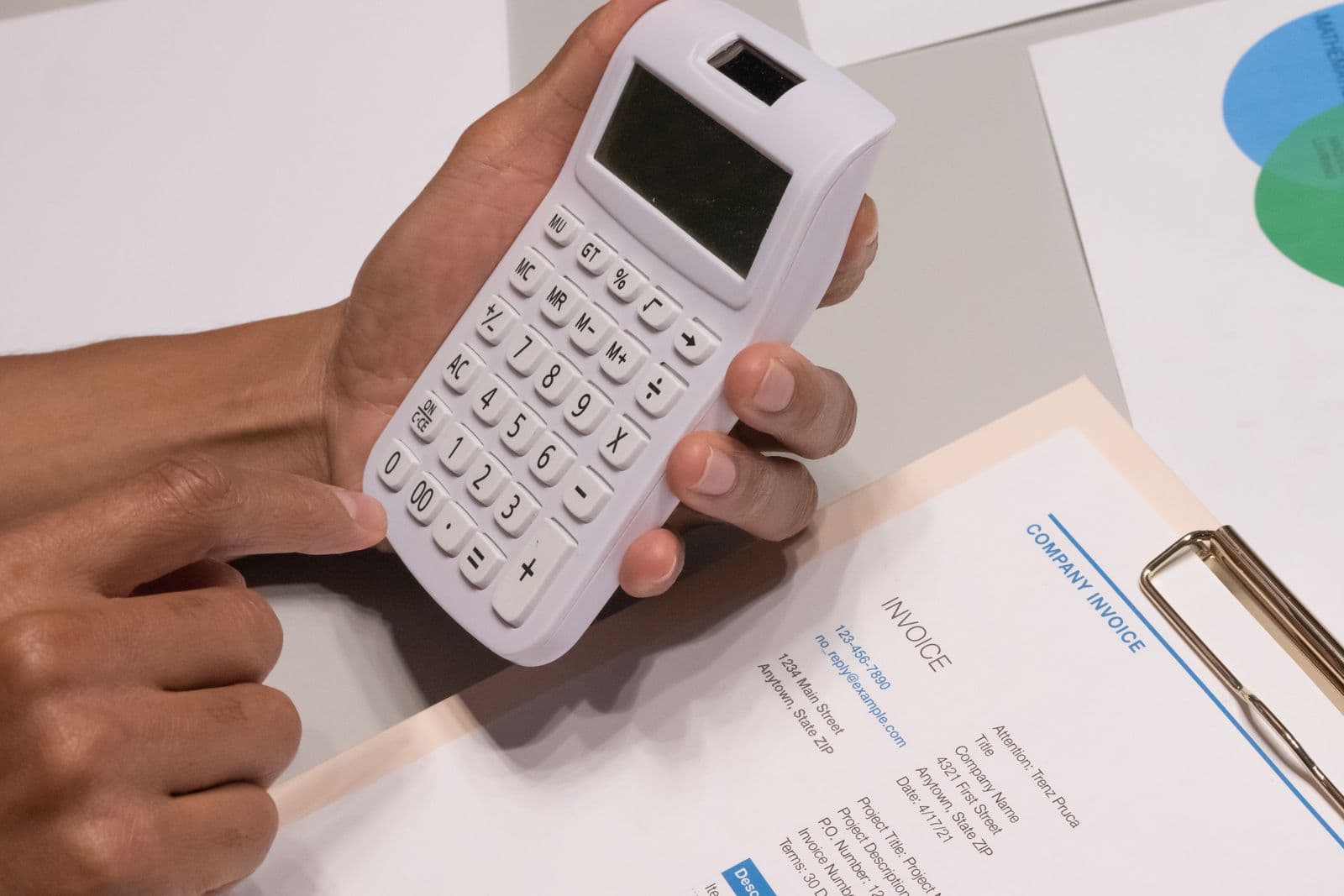 Hands using a calculator next to an invoice